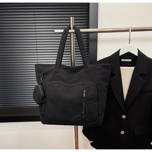 Dettaglio della borsa tote in velluto nero con tasca zip e mini custodia rotonda appesa