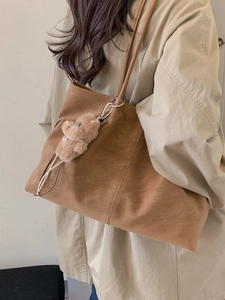Classic brown matte faux leather tote bag with long straps and a plush bear pendant