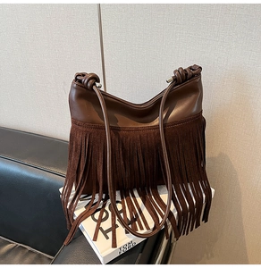 Dettaglio borsa a secchiello marrone scuro con nappe in camoscio e tracolla con nodi