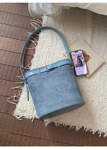 Détail d'un sac seau bleu clair avec texture en daim et boucle argentée sur un tapis