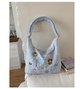 Détail du sac Hobo matelassé bleu clair avec broderie de chiot et large bandoulière