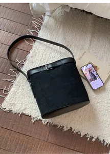 Détail d'un sac seau en daim noir avec bandoulière en cuir sur tapis moelleux