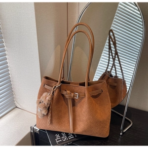 Detailaufnahme der braun geflochtenen Ledertasche mit Silberschnalle und Bärenanhänger