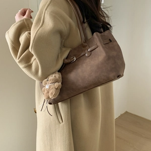 Brown vintage tote bag with metal buckle detail and cute plush bear charm on a model