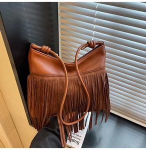 Dettaglio di una borsa a tracolla in pelle marrone con lunghe frange e stile boho