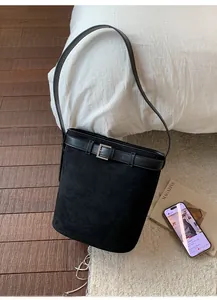 Détail d'un sac seau en daim noir avec boucle de ceinture en cuir et bandoulière fine