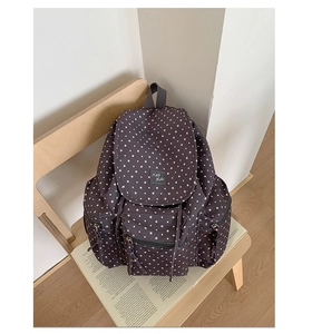 Detail of black canvas backpack featuring white star patterns and multi-pocket structure
