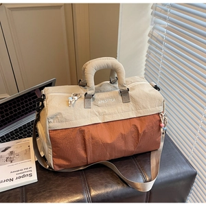 Détail du sac de voyage beige et rouge brique en nylon avec des poignées robustes