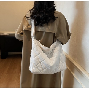 Detail view of white quilted crossbody tote bag with adjustable strap on a female model