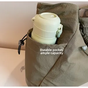 Detail view of large nylon tote bag showing a side pocket holding a water bottle