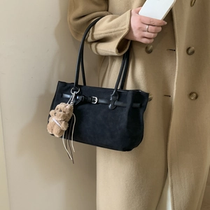 Detail of black matte tote bag with decorative bear pendant and pearl necklace accessory