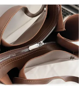 Detail view of the smooth silver metal zipper and dark brown leather texture on tote bag