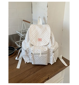 Detail of white canvas backpack with pink star pattern and functional side pockets