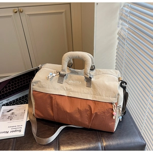 Détail d'un grand sac de voyage bicolore sur un banc en cuir avec décor lifestyle
