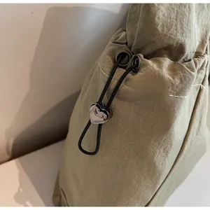 Detail of grey-green nylon tote with drawstring closure and heart-shaped metal toggle