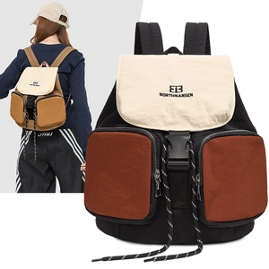 Detail view of stylish tri-color backpack showing black, white, and brown zip pockets