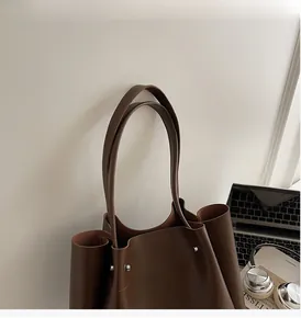 Detail of dark brown tote bag with durable slender handles and reinforced metal rivets