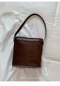 Détail du sac seau minimaliste en daim marron foncé avec bandoulière en cuir