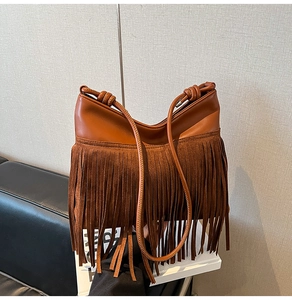 Dettaglio della borsa a tracolla marrone con frange in pelle scamosciata e cinturino annodato