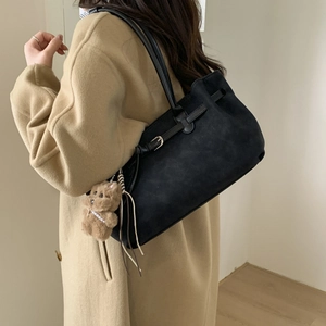 Detail of a black large tote bag featuring a plush bear pendant and soft matte texture