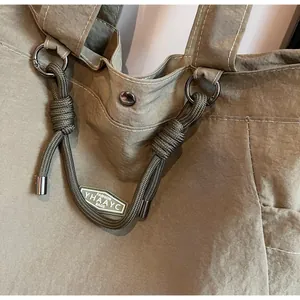 Detailed view of army green nylon tote featuring woven rope handles and brand logo tag