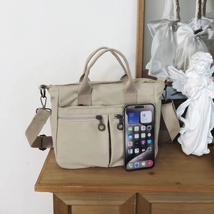 Detail view of nylon tote bag with front zipper pockets and adjustable shoulder strap