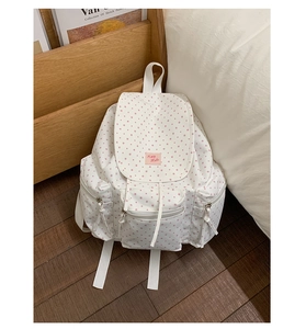 Detailed view of white polka dot backpack with drawstring closure and pink star patterns