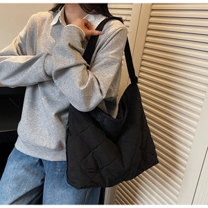 Detail of black quilted large capacity shoulder bag showing nylon texture and stitching