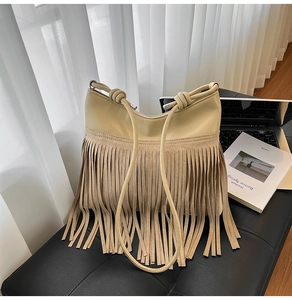 Dettaglio ravvicinato di una borsa a tracolla beige con frange in pelle scamosciata di qualità