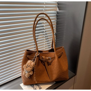 Detail der braunen geflochtenen Leder-Tote mit Bärenanhänger und Schultergurt