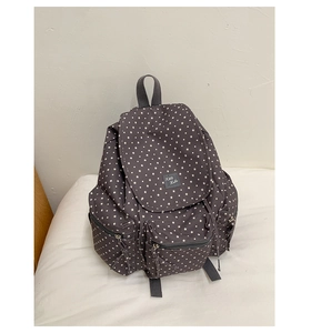 Macro view of dark grey star pattern backpack featuring a front zipper pocket and logo label