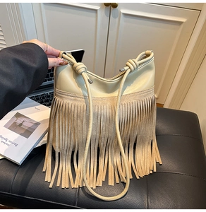 Dettaglio della borsa bohémien color crema con lunghe frange e tracolla con nodi