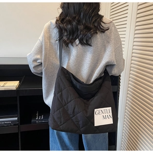Close-up of black quilted tote bag with white GENTLE MAN label and rhombus pattern