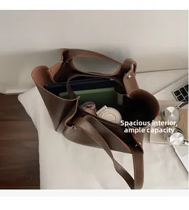 Top view of spacious dark brown tote bag interior with tablet, umbrella and notebooks