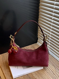 Vintage burgundy suede tote bag with cherry charm on a wooden table setup