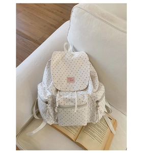 Close-up of white canvas backpack with pink star patterns and KMB Hello woven label