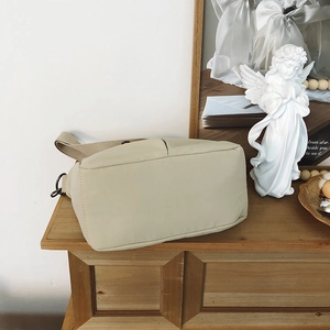 Detail view of the wide beige nylon bag base with strap on a rustic wooden table