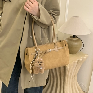 Close-up of vintage brown suede shoulder bag with decorative strap and plush dog charm