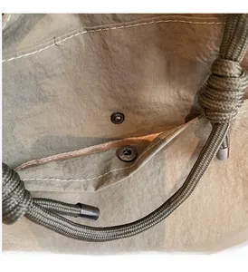 Close-up of khaki nylon tote fabric with metal snap button and woven rope handle