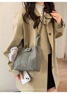 Detail of retro sage green bucket bag with white contrast stitching and plush bunny charm