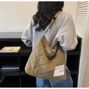 Detail of khaki quilted tote bag featuring Gentle Woman logo and puffer texture