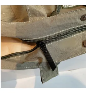 Detailed macro view of the smooth metal zipper and olive green quilted nylon fabric