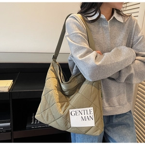 Detail of olive green quilted tote bag with white Gentle Woman canvas logo patch