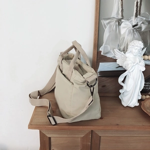 Close-up of beige nylon tote bag on wooden cabinet with adjustable wide shoulder strap