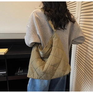 Detail view of large olive green quilted tote bag with diamond stitching on a model