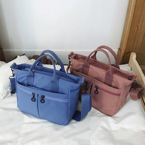 Detail of dual front zipper pockets and texture on a blue nylon crossbody shoulder bag