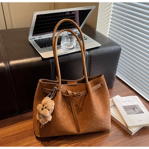 Detail der geflochtenen braunen Leder-Tote-Bag mit Plüsch-Hundeanhänger und Metallschnalle