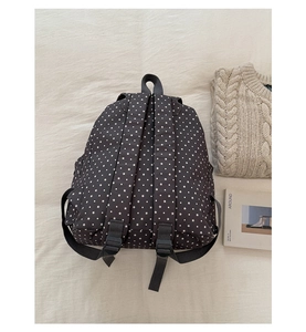 Detail shot of black floral backpack with white star patterns and adjustable straps