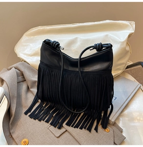 Dettaglio della borsa a secchiello con frange nere, inserti in pelle e tracolla annodata