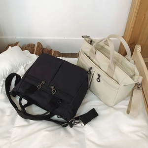 Close-up of black and beige nylon shoulder bags with circular metal zipper pulls